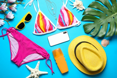 Photo of Flat lay composition with bikini, smartphone and beach objects on color background