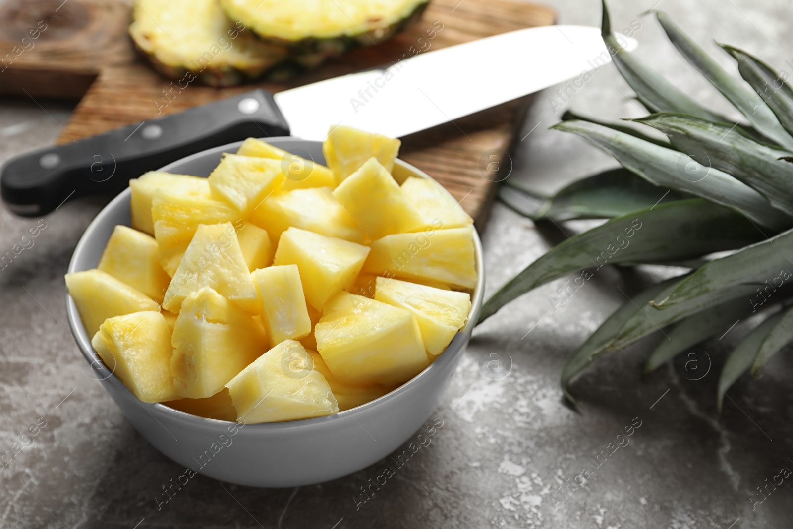 Photo of Bowl with fresh sliced pineapple on table