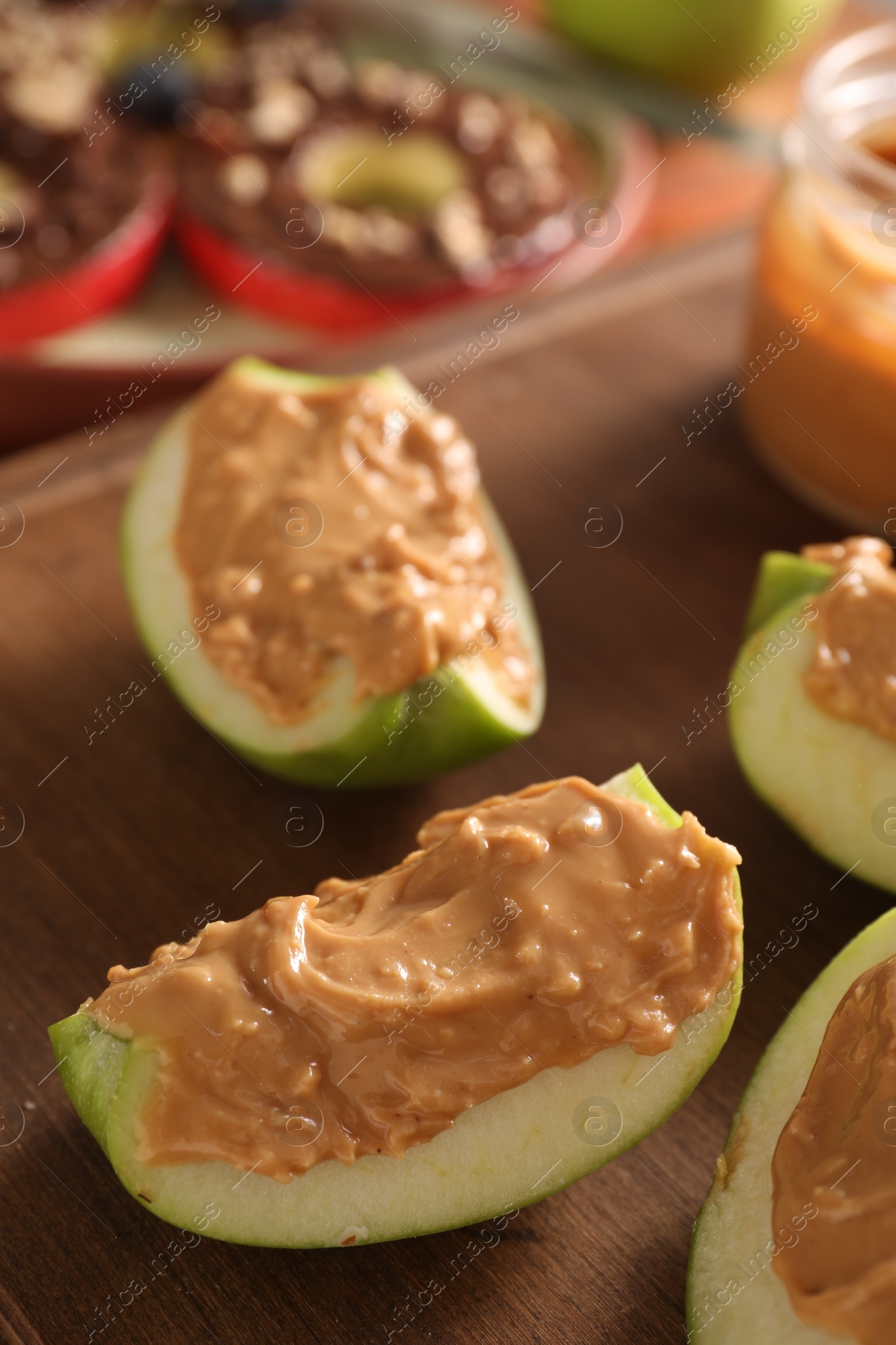 Photo of Slices of fresh apple with nut butter on wooden board, closeup