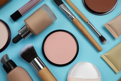 Photo of Face powders and other decorative cosmetic products on light blue background, flat lay