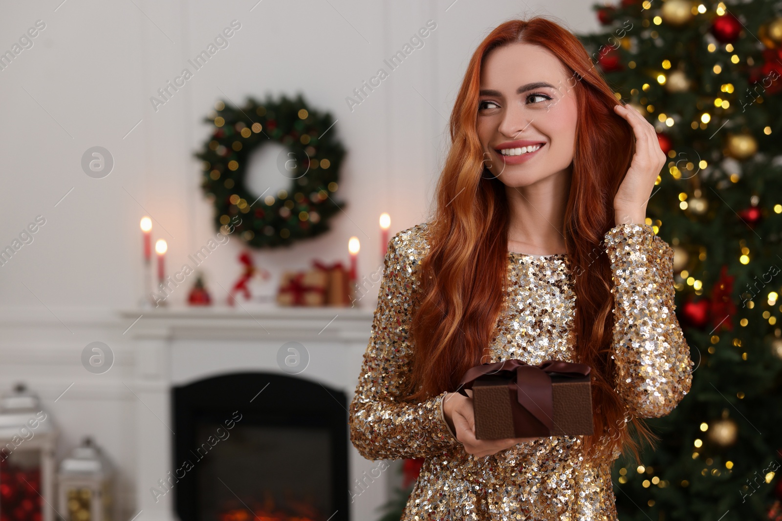 Photo of Happy young woman with Christmas gift at home, space for text