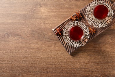 Photo of Glasses of traditional Turkish tea in vintage holders and anise stars on wooden table, top view. Space for text
