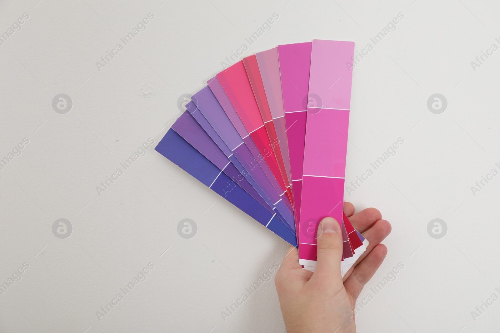 Photo of Man with palette choosing color for painting wall indoors, closeup. Interior design