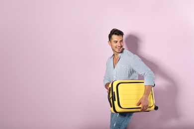 Photo of Young man with suitcase on color background. Space for text