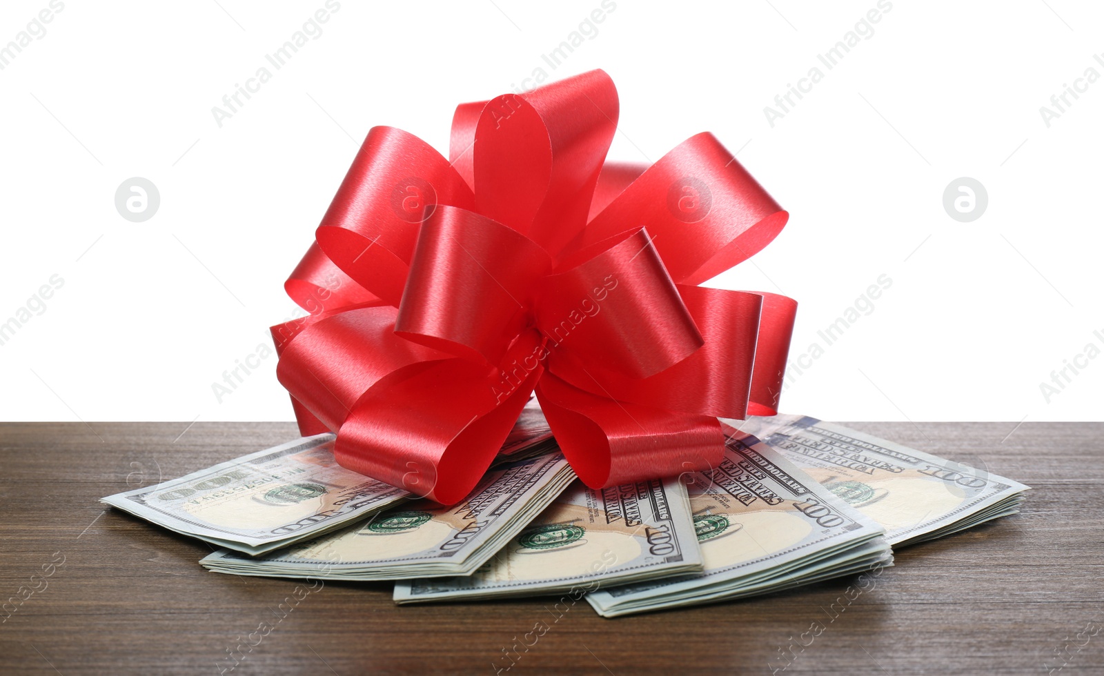 Dollar bills with red bow on wooden table against white background Photo of Dollar bills with red bow on wooden table against white background