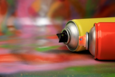 Photo of Cans of different graffiti spray paints on color background, closeup. Space for text