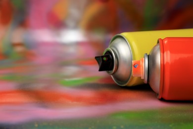 Cans of different graffiti spray paints on color background, closeup. Space for text