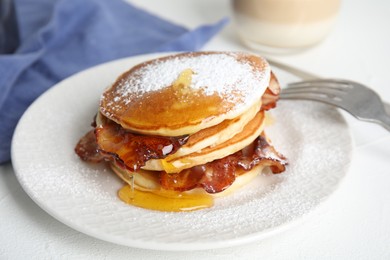 Photo of Delicious pancakes with maple syrup, sugar powder and fried bacon on white table, closeup