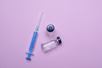 Photo of Disposable syringe and vials with medicine on violet background, flat lay