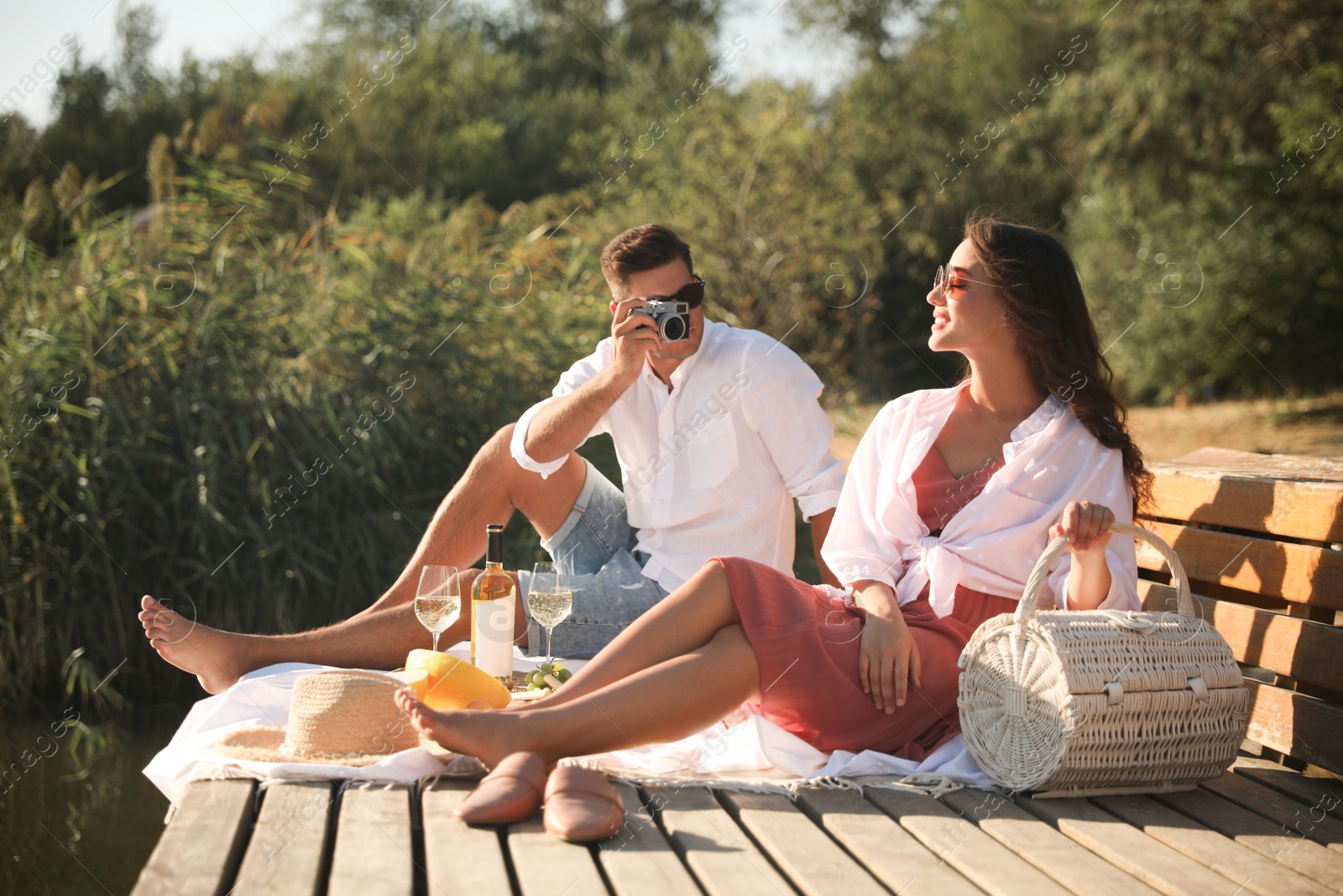 Photo of Man taking picture of girlfriend on pier at picnic