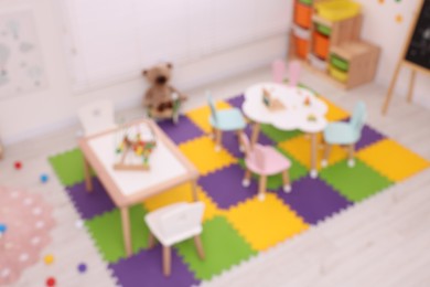 Stylish kindergarten interior with toys and modern furniture, blurred view