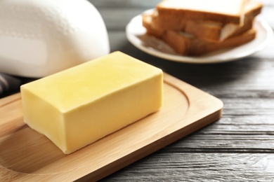 Photo of Wooden board with fresh butter on wooden table