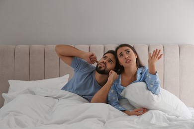 Young couple suffering from noisy neighbours in bed at home