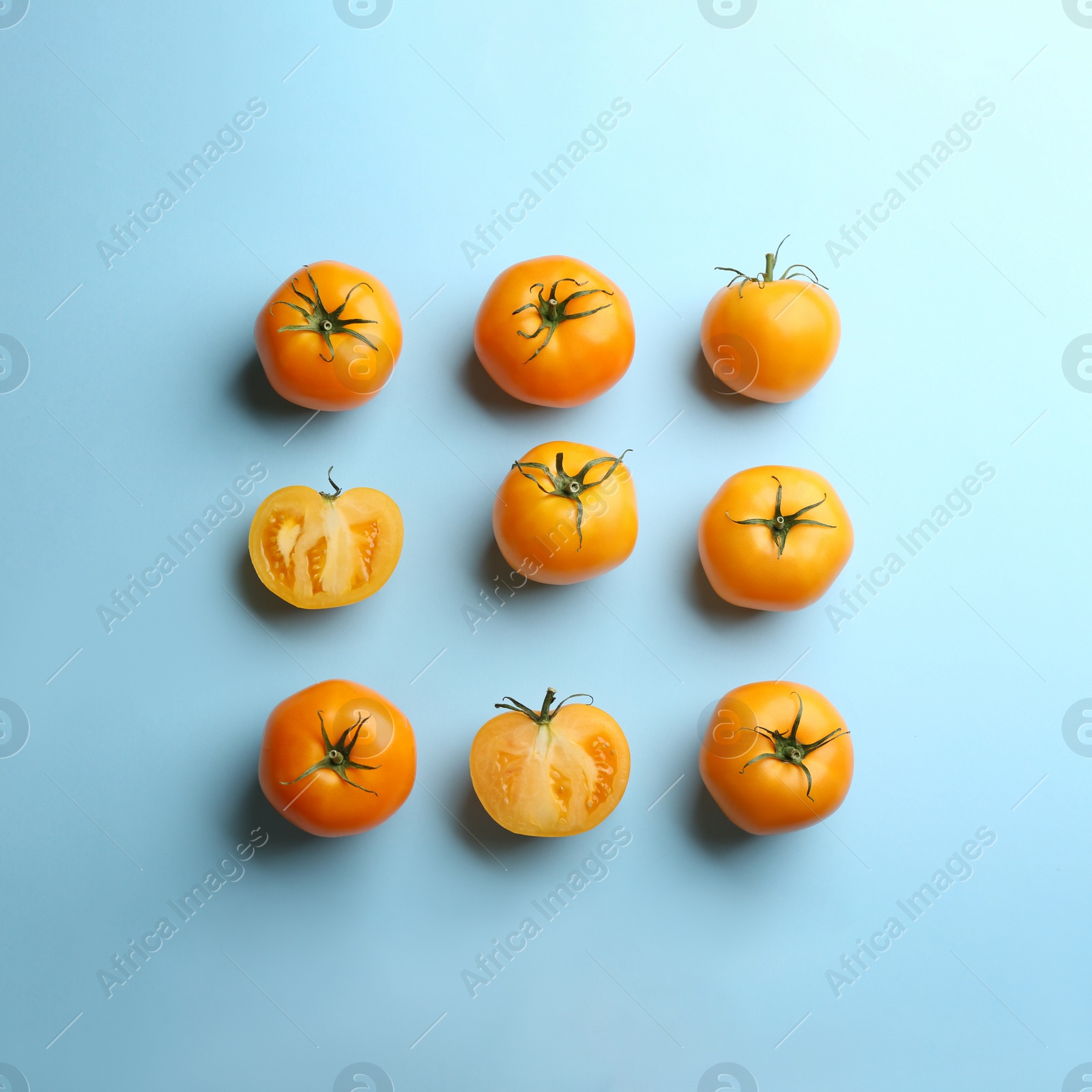 Photo of Yellow tomatoes on light blue background, flat lay