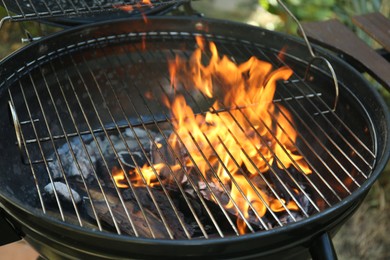 Photo of New modern barbecue grill with burning firewood outdoors, closeup