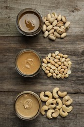 Photo of Tasty nut butters in jars and raw nuts on wooden table, flat lay