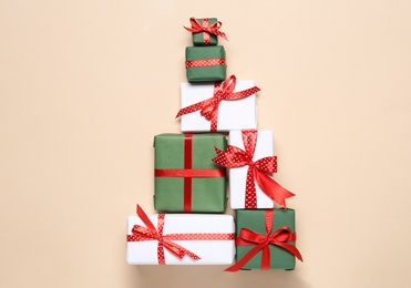 Photo of Christmas tree shape of gift boxes on beige background, flat lay