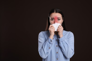 Young woman blowing nose in tissue on dark background, space for text. Cold symptoms