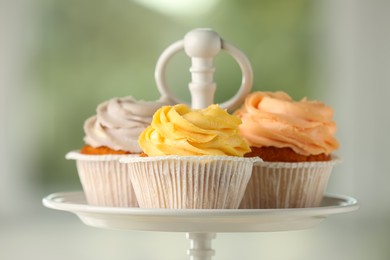 Photo of Dessert stand with tasty cupcakes indoors, closeup