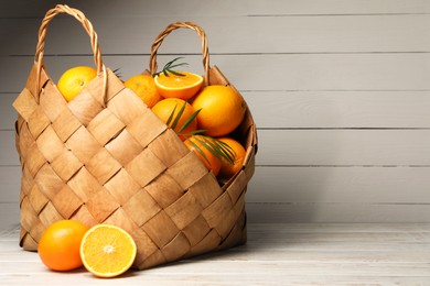 Photo of Many whole and cut oranges on white wooden table. Space for text