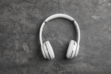 Photo of Stylish modern headphones on concrete background, top view