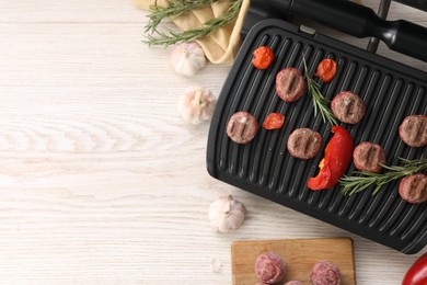 Photo of Electric grill with vegetables, meat balls and rosemary on wooden table, flat lay. Space for text