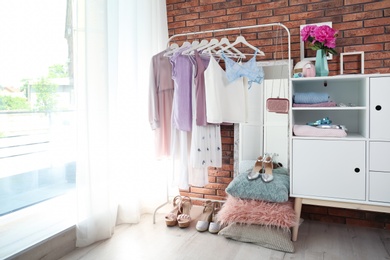 Photo of Stylish dressing room interior with clothes on rack