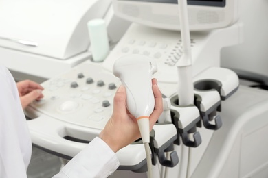 Professional sonographer using modern ultrasound machine in clinic, closeup