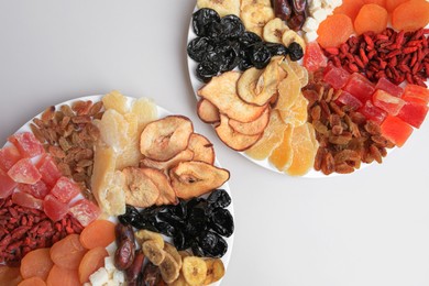 Plates with different dried fruits on white background, top view