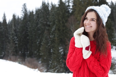 Photo of Happy young woman in warm clothes outdoors, space for text. Winter vacation