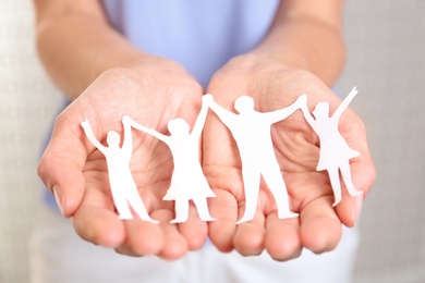 Young woman holding paper family figure, closeup of hands