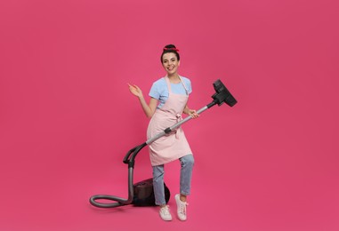Photo of Housewife with vacuum cleaner on pink background