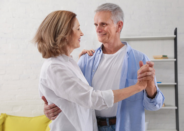 Photo of Happy senior couple dancing together in living room