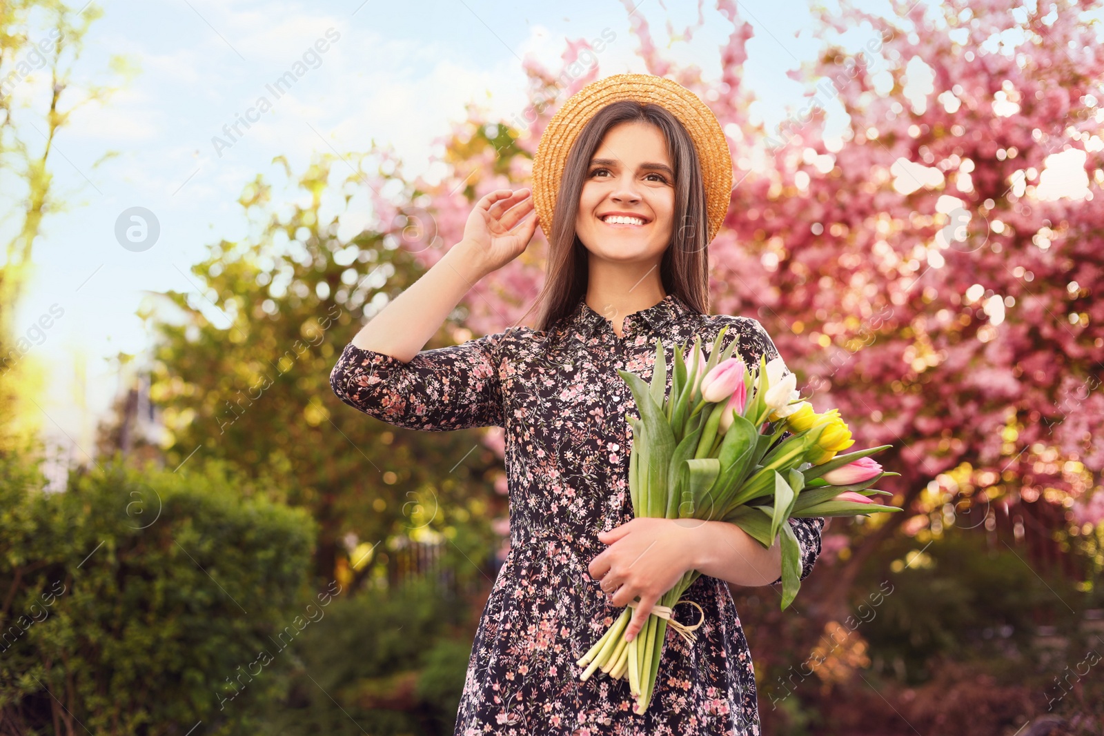 Photo of Beautiful young woman with bouquet of tulips in park on sunny day