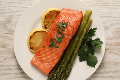 Photo of Tasty grilled salmon with asparagus and lemon on white wooden table, top view