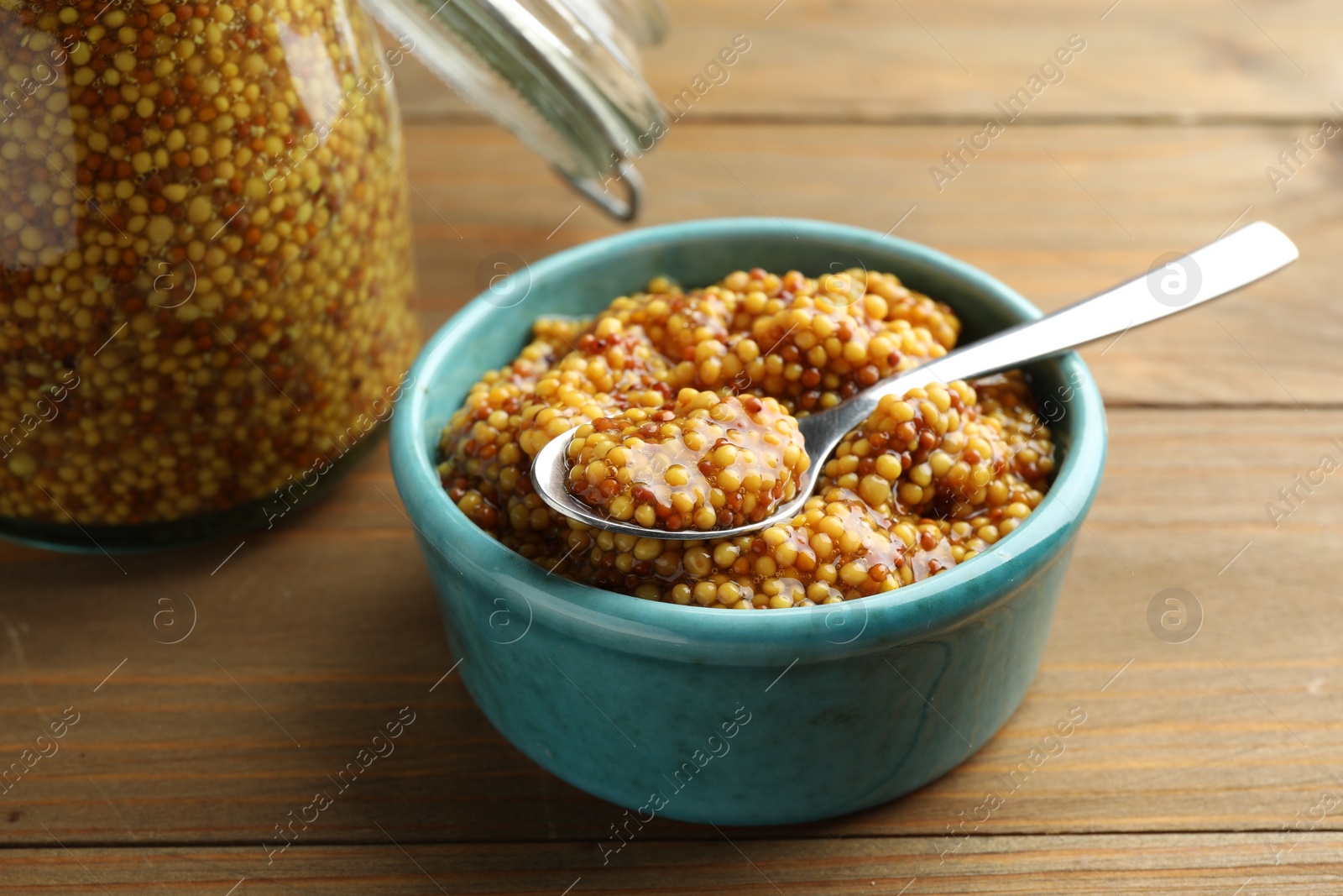 Photo of Whole grain mustard in bowl and spoon on wooden table