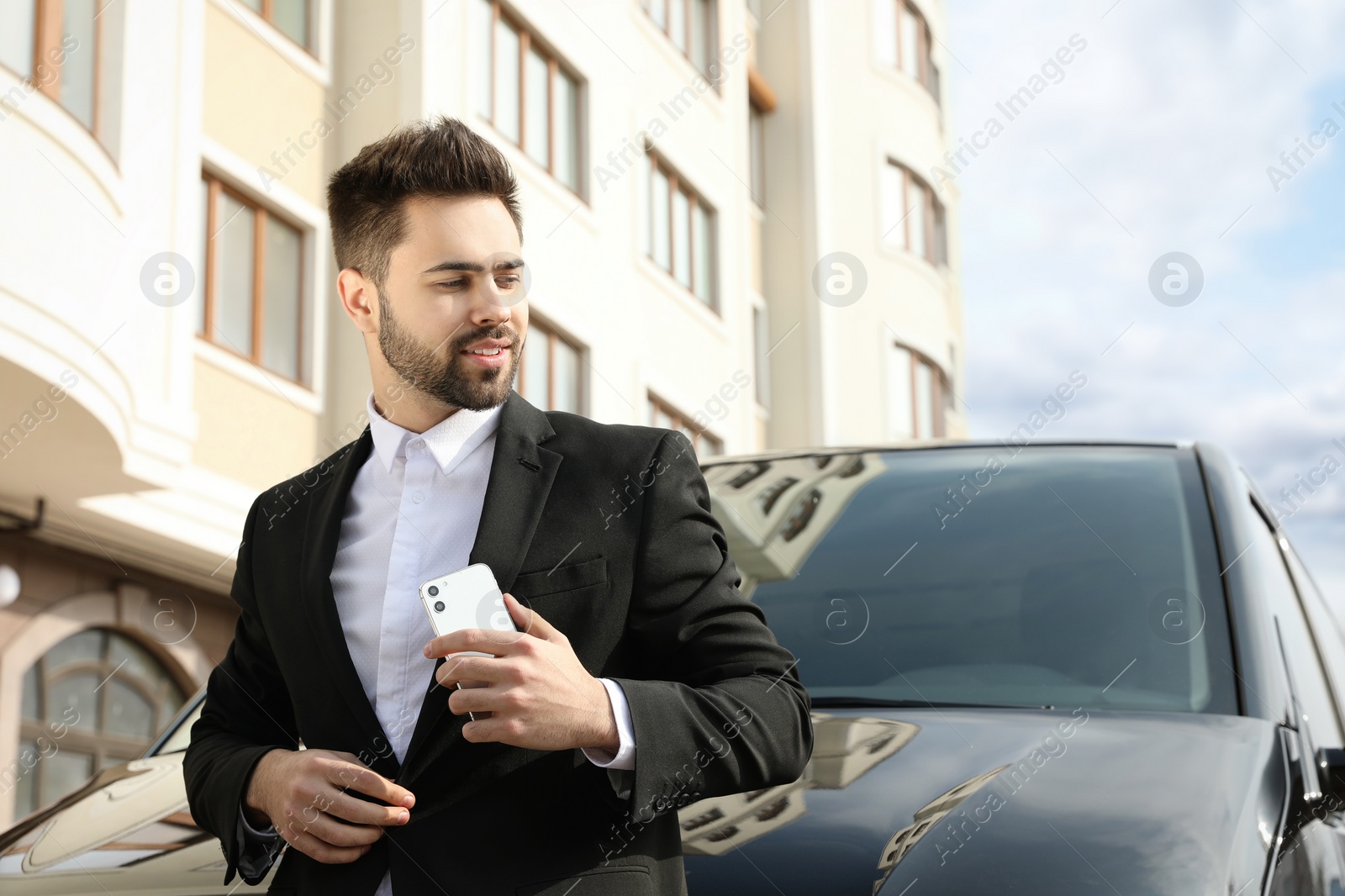 Photo of Handsome young man with smartphone near modern car outdoors