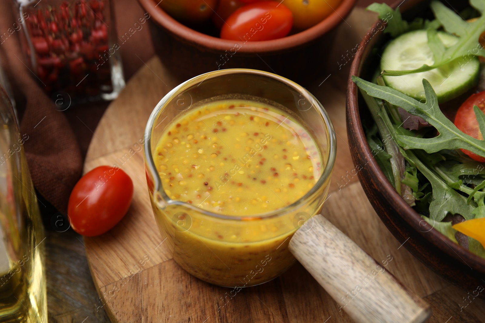 Photo of Tasty vinegar based sauce (Vinaigrette), salad and tomatoes on wooden table, closeup