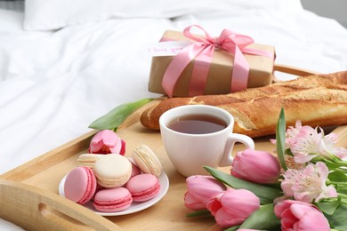 Photo of Delicious breakfast, flowers, gift box and card with phrase I Love You on bed