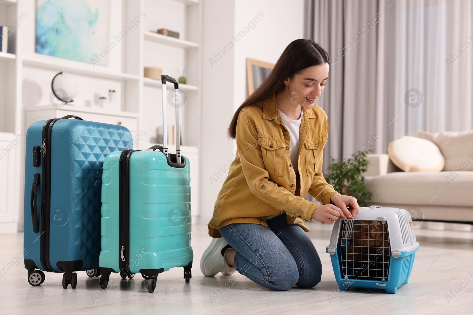 Photo of Smiling woman closing carrier with her pet before travelling indoors