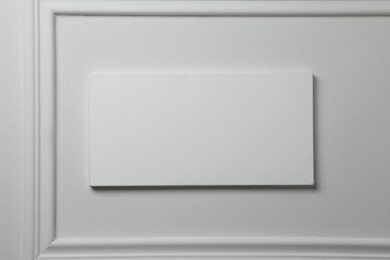 Photo of Blank canvas hanging on white wall, space for text