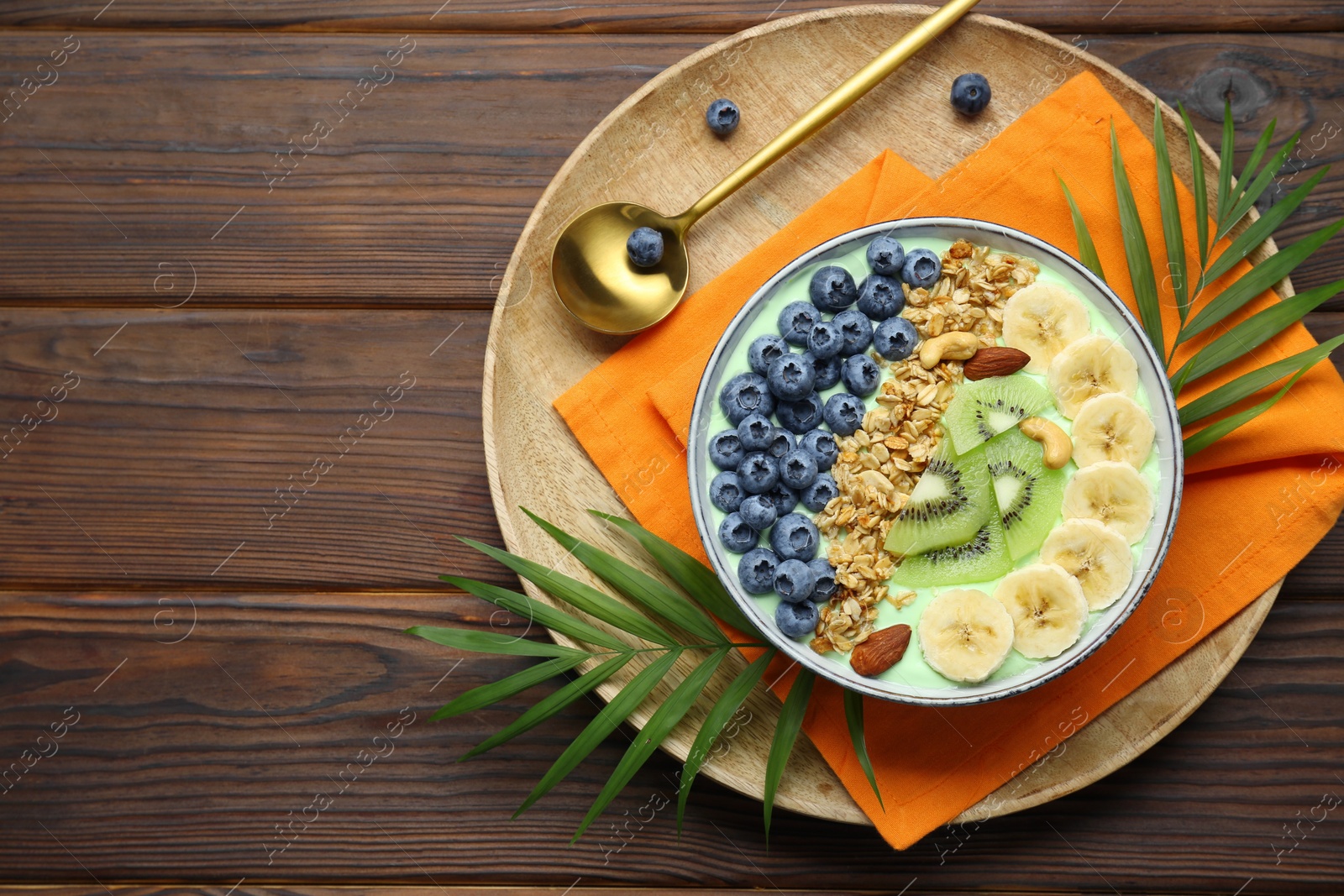 Photo of Tasty smoothie bowl with fresh fruits and oatmeal served on wooden table, top view. Space for text