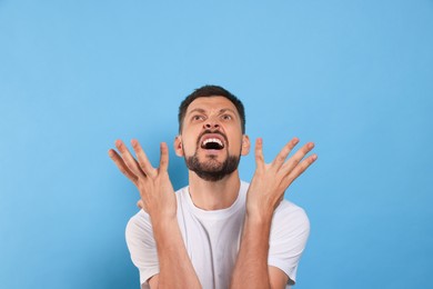 Photo of Aggressive man shouting on light blue background