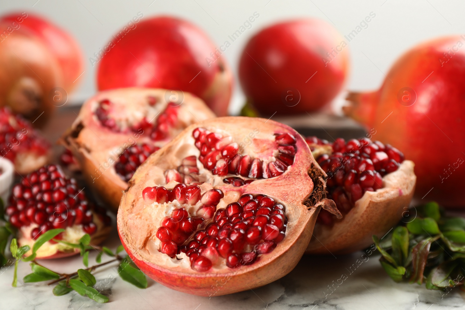 Photo of Delicious ripe pomegranates on white table, closeup