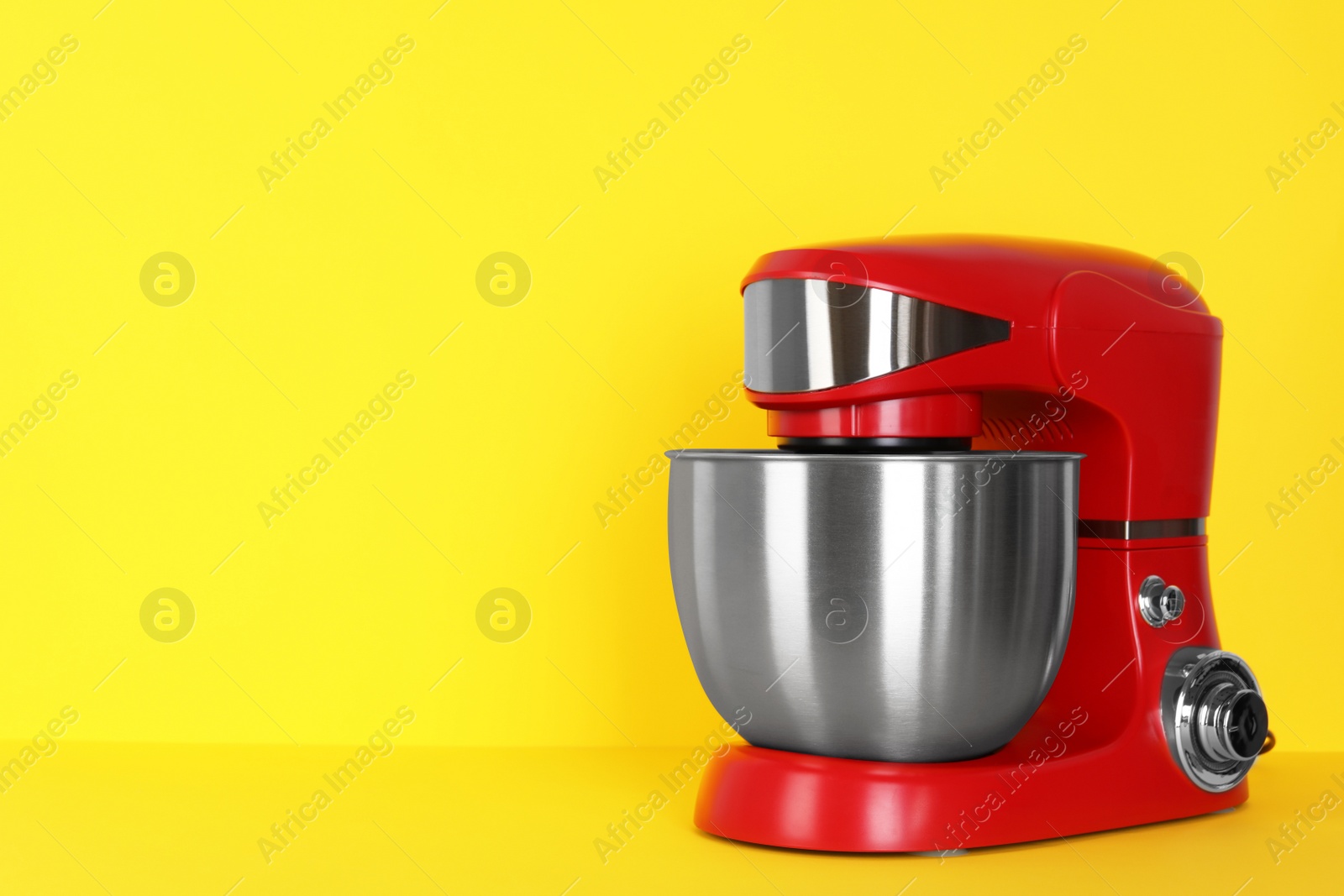 Photo of Modern red stand mixer on yellow background, space for text