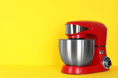 Photo of Modern red stand mixer on yellow background, space for text