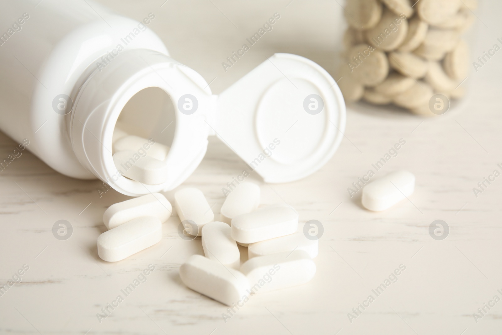 Photo of Bottle with vitamin pills on light table, closeup