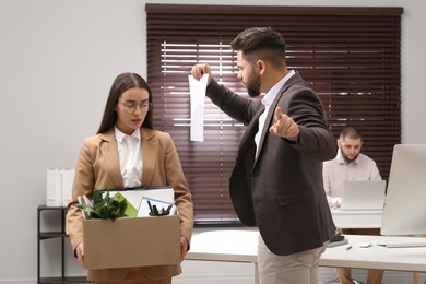 Boss dismissing young woman from work in office