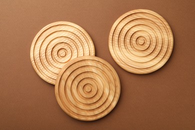 Stylish wooden cup coasters on brown background, flat lay