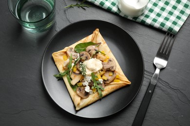 Delicious breakfast with thin pancakes on black table, flat lay